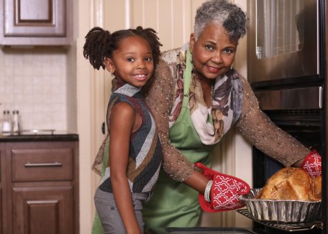 African descent family in home kitchen cooking Thanksgiving dinner.