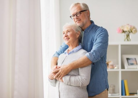 happy-senior-couple-looking-through-window-at-home